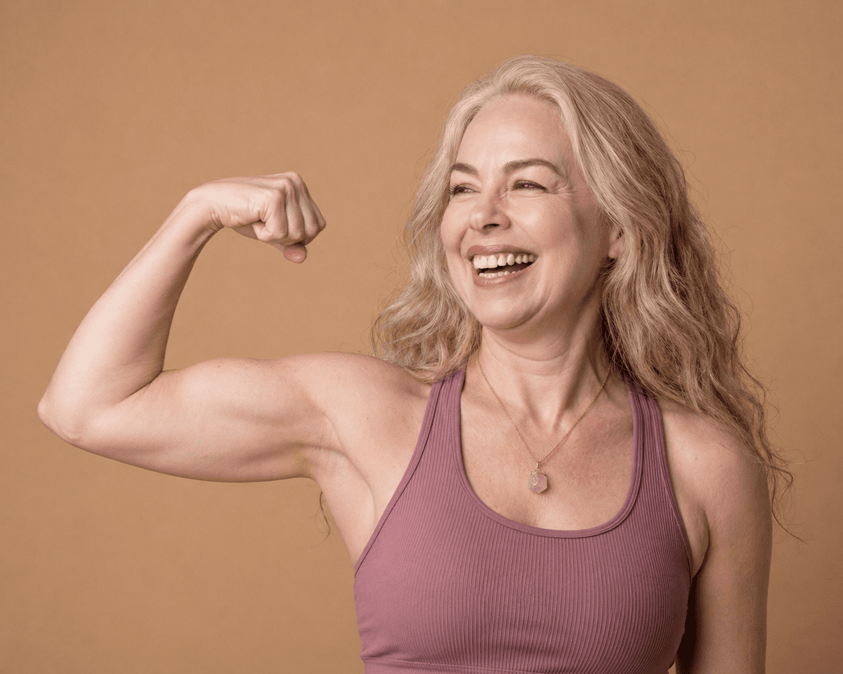 Mujer sonriente flexionando el brazo